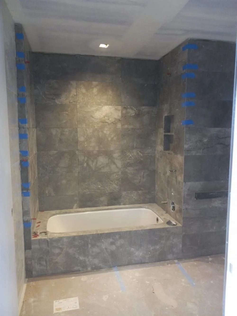 Bathroom renovation in progress with a stone-tiled tub surround